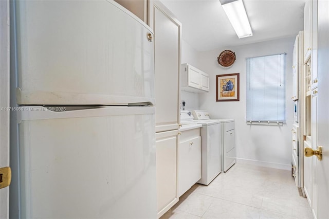 clothes washing area featuring cabinets, separate washer and dryer, and light tile patterned flooring