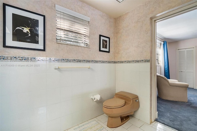 bathroom featuring tile patterned flooring, tile walls, and toilet