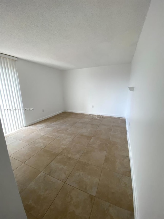 tiled spare room featuring a textured ceiling