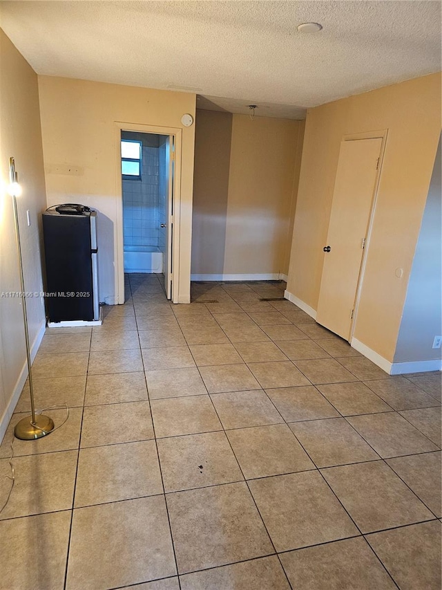 tiled empty room with a textured ceiling