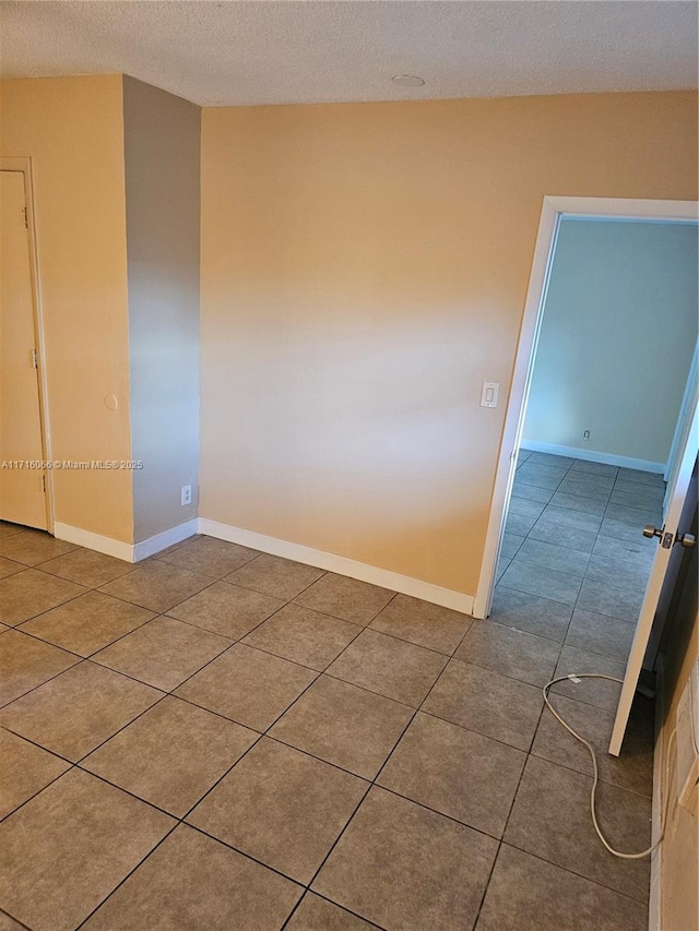 spare room with a textured ceiling and tile patterned floors