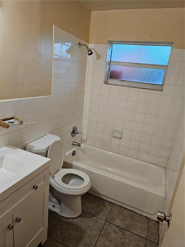 full bathroom with vanity, tile patterned floors, tiled shower / bath combo, toilet, and tile walls