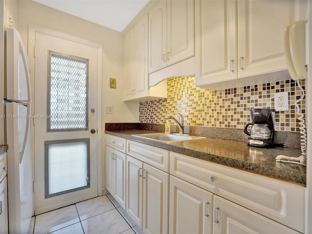 kitchen with white fridge, dark stone countertops, sink, and tasteful backsplash