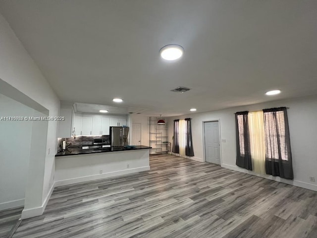 kitchen featuring white cabinetry, light hardwood / wood-style floors, kitchen peninsula, stainless steel refrigerator with ice dispenser, and tasteful backsplash