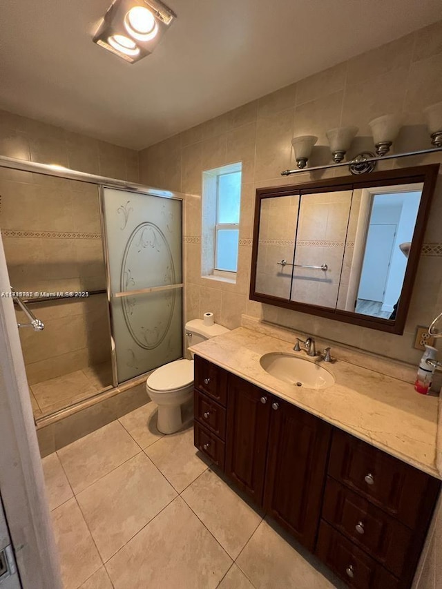 bathroom with tile patterned flooring, vanity, tile walls, toilet, and walk in shower