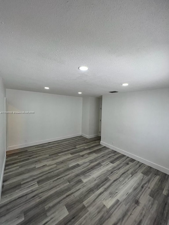 empty room featuring a textured ceiling and dark hardwood / wood-style flooring