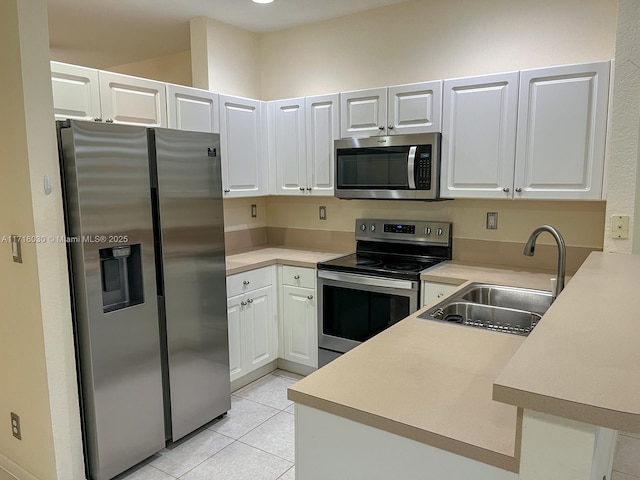 kitchen with white cabinets, sink, light tile patterned floors, appliances with stainless steel finishes, and kitchen peninsula