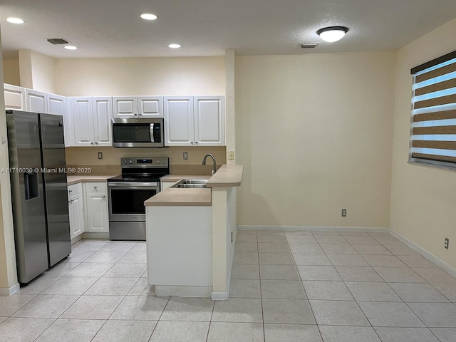 kitchen with kitchen peninsula, white cabinetry, sink, and appliances with stainless steel finishes