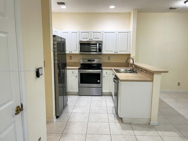 kitchen featuring kitchen peninsula, appliances with stainless steel finishes, white cabinets, and sink