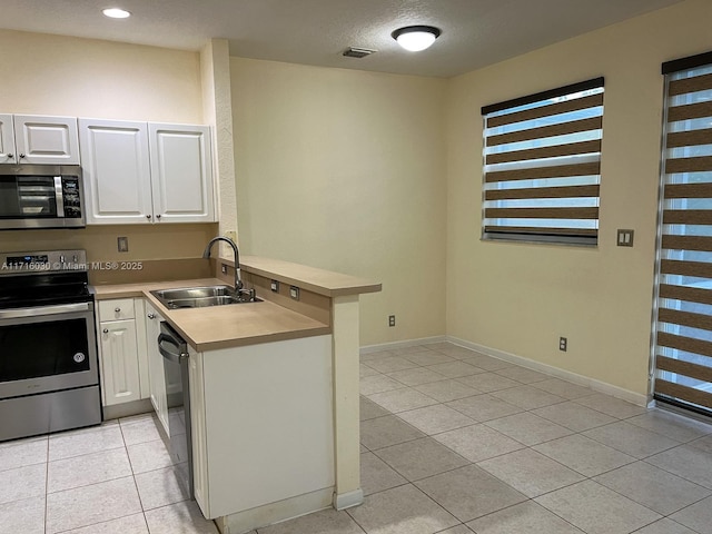 kitchen with white cabinetry, sink, stainless steel appliances, kitchen peninsula, and light tile patterned floors