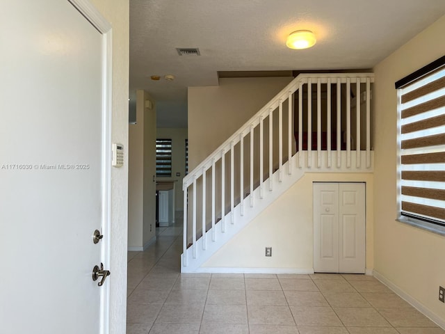 stairs with tile patterned floors and a textured ceiling