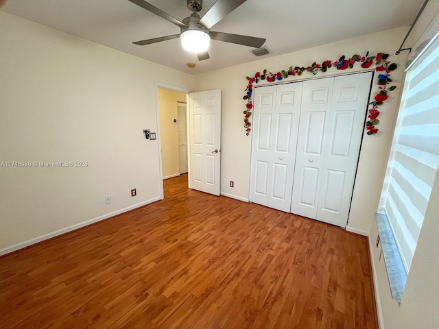 unfurnished bedroom with hardwood / wood-style floors, ceiling fan, and a closet