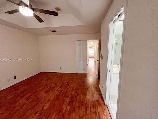 unfurnished room featuring light hardwood / wood-style floors, a raised ceiling, and ceiling fan