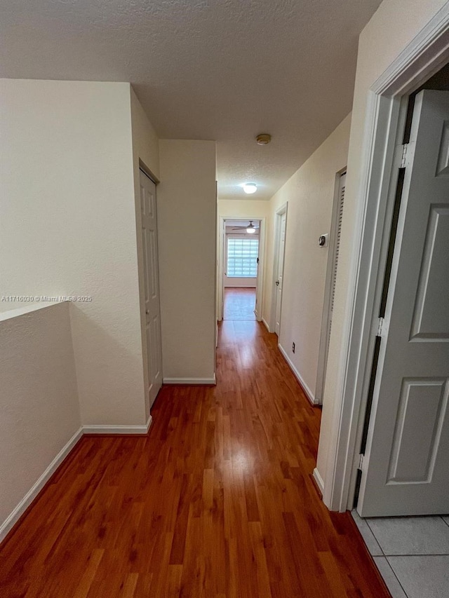 hallway with wood-type flooring and a textured ceiling