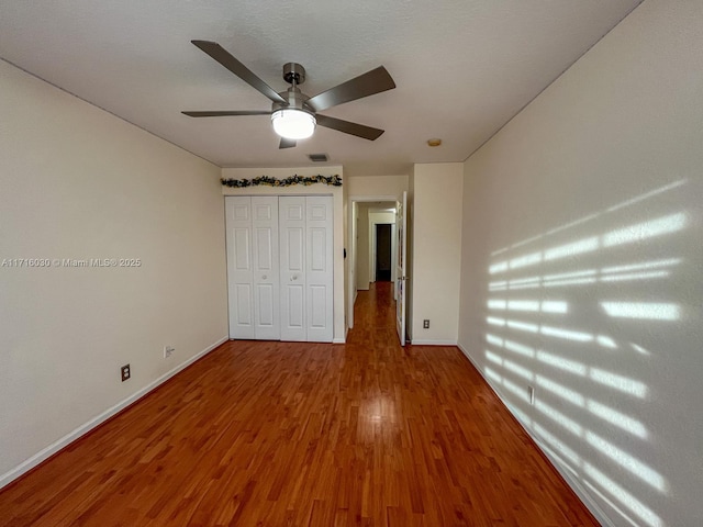 unfurnished bedroom featuring ceiling fan, wood-type flooring, and a closet