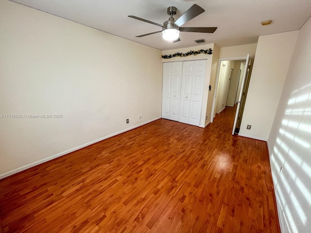 unfurnished bedroom with ceiling fan, a closet, and dark hardwood / wood-style floors