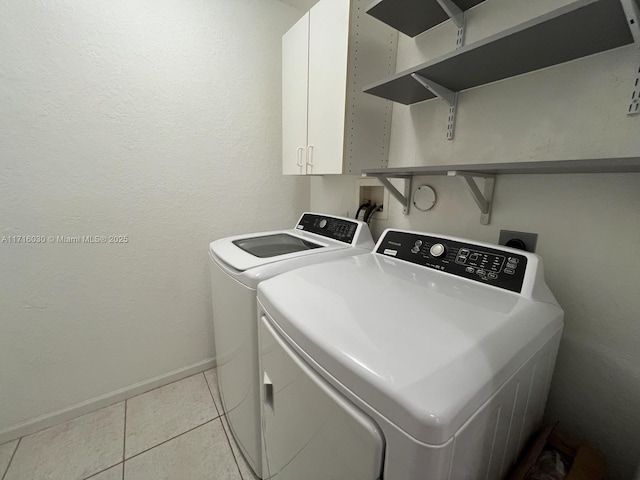 washroom with washer and clothes dryer, cabinets, and light tile patterned floors