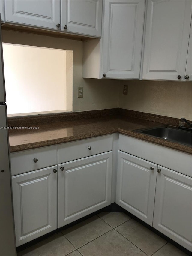 kitchen featuring sink, white fridge, white cabinetry, and light tile patterned flooring