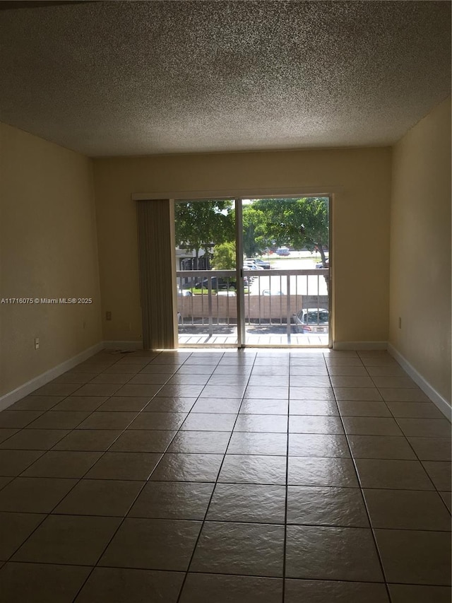 unfurnished room featuring a textured ceiling and dark tile patterned floors