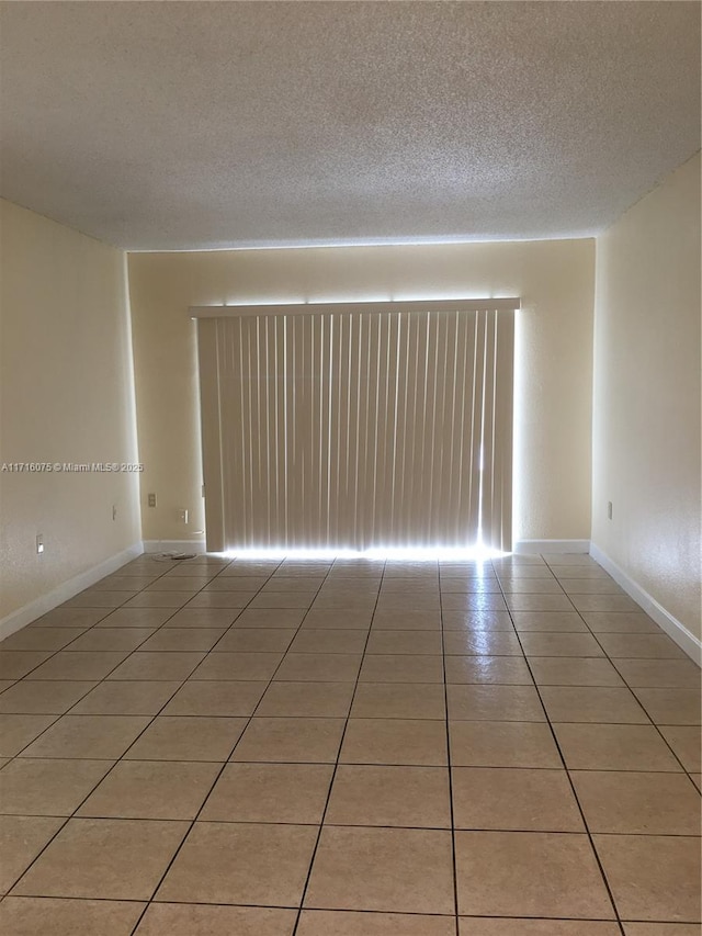 unfurnished room with light tile patterned floors and a textured ceiling