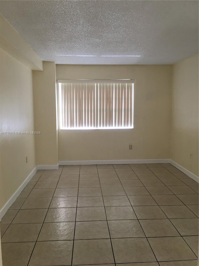 tiled empty room with a textured ceiling