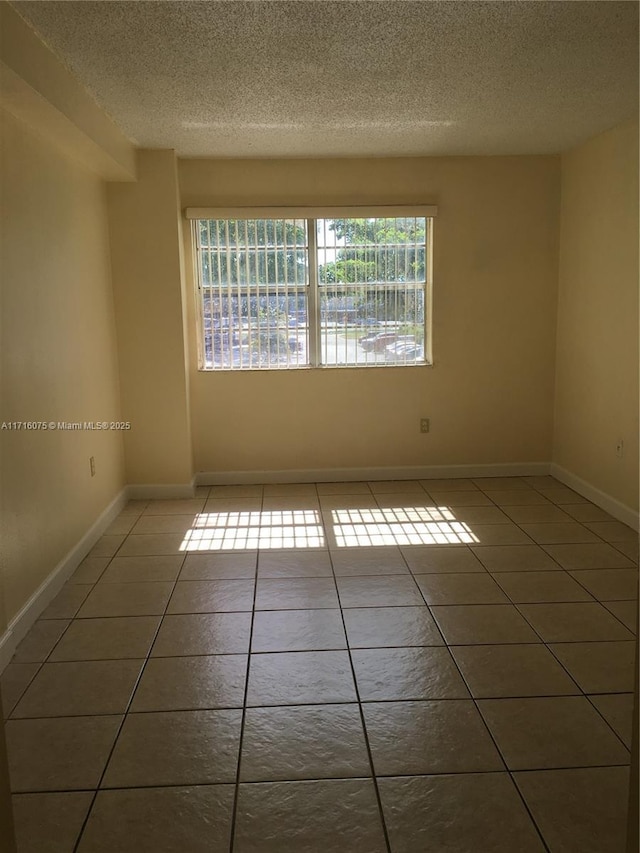 tiled empty room with a textured ceiling and plenty of natural light