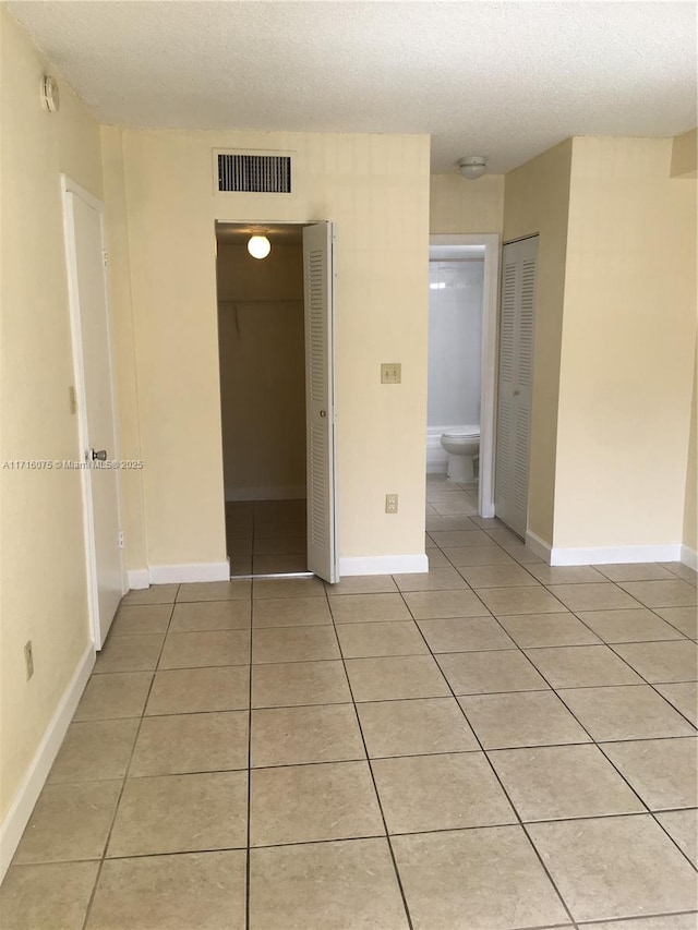 unfurnished room featuring light tile patterned floors and a textured ceiling