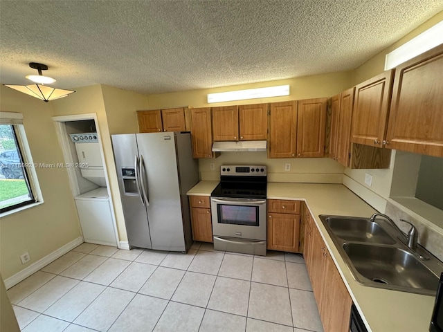 kitchen with sink, light tile patterned floors, a textured ceiling, stacked washer / dryer, and stainless steel appliances