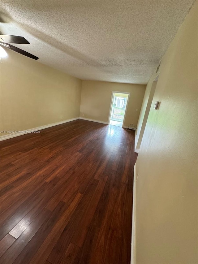 empty room featuring dark hardwood / wood-style flooring, a textured ceiling, and ceiling fan