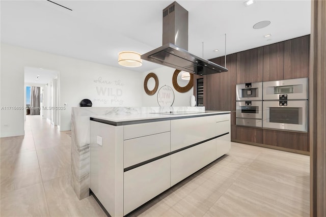 kitchen with white cabinetry, double oven, dark brown cabinets, black electric stovetop, and island exhaust hood