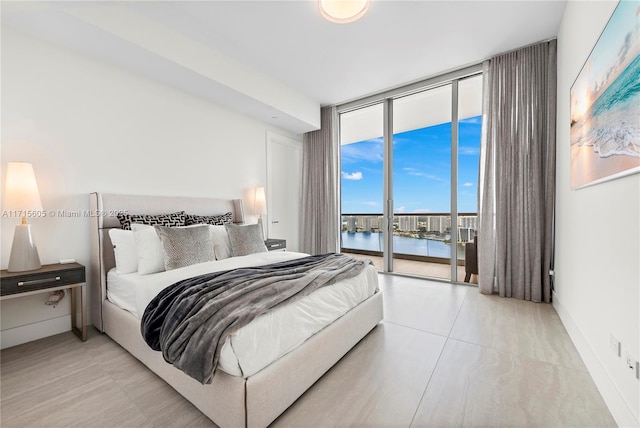 bedroom with access to exterior, a wall of windows, and a water view