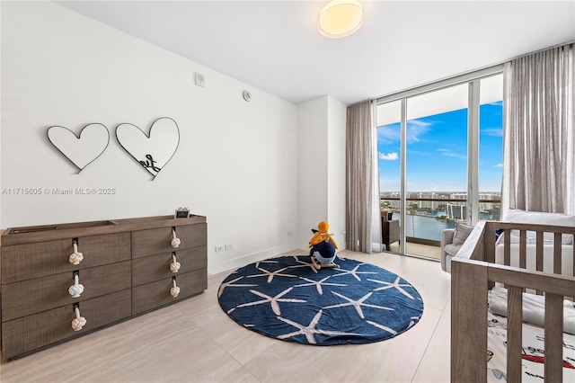 bedroom with expansive windows, light tile patterned flooring, and a water view