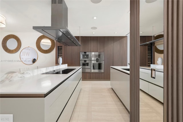 kitchen with island range hood, wooden walls, double oven, black electric stovetop, and dark brown cabinetry