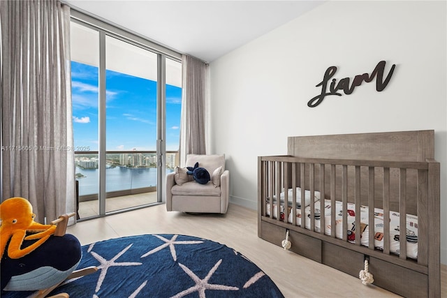 bedroom with multiple windows, access to exterior, floor to ceiling windows, and a water view