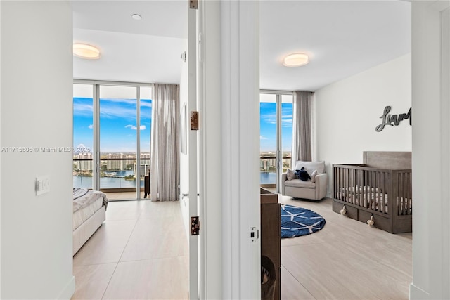 bedroom featuring light tile patterned floors, floor to ceiling windows, and a water view