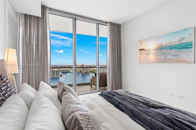 bedroom featuring a water view, a wall of windows, and access to exterior