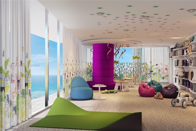 playroom featuring a view of the beach, carpet floors, expansive windows, and a water view