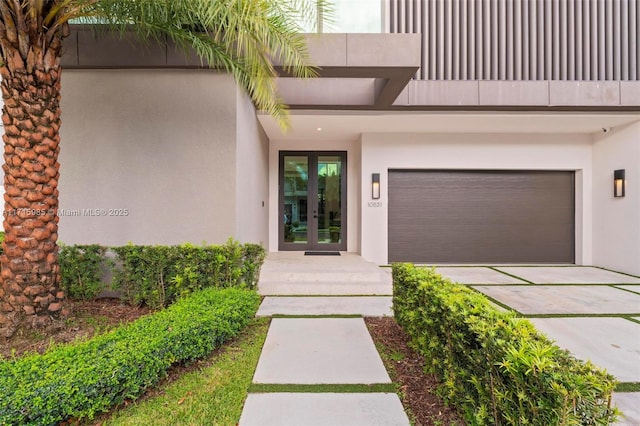 view of exterior entry with a garage, a balcony, and french doors