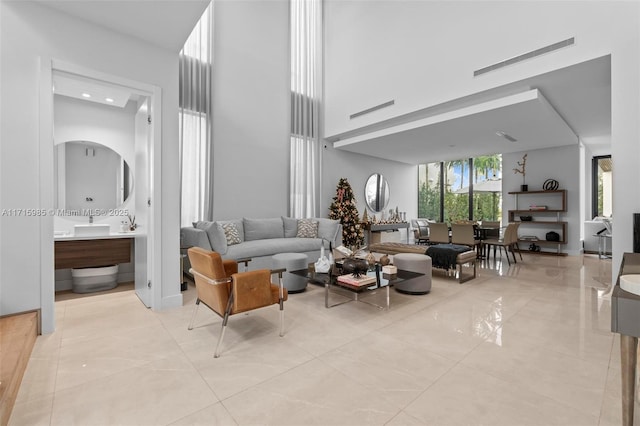 living room with a towering ceiling and light tile patterned floors