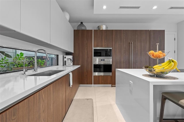 kitchen with light tile patterned flooring, sink, white cabinets, and oven