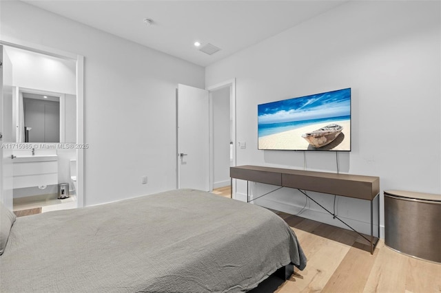 bedroom featuring ensuite bathroom and hardwood / wood-style floors