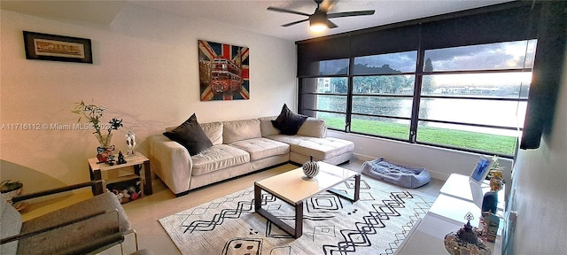 living room featuring a water view, ceiling fan, and light tile patterned flooring