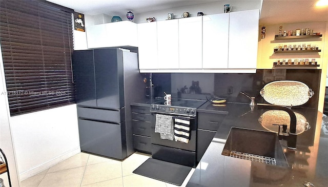 kitchen with white cabinetry, black range with electric cooktop, backsplash, refrigerator, and light tile patterned floors