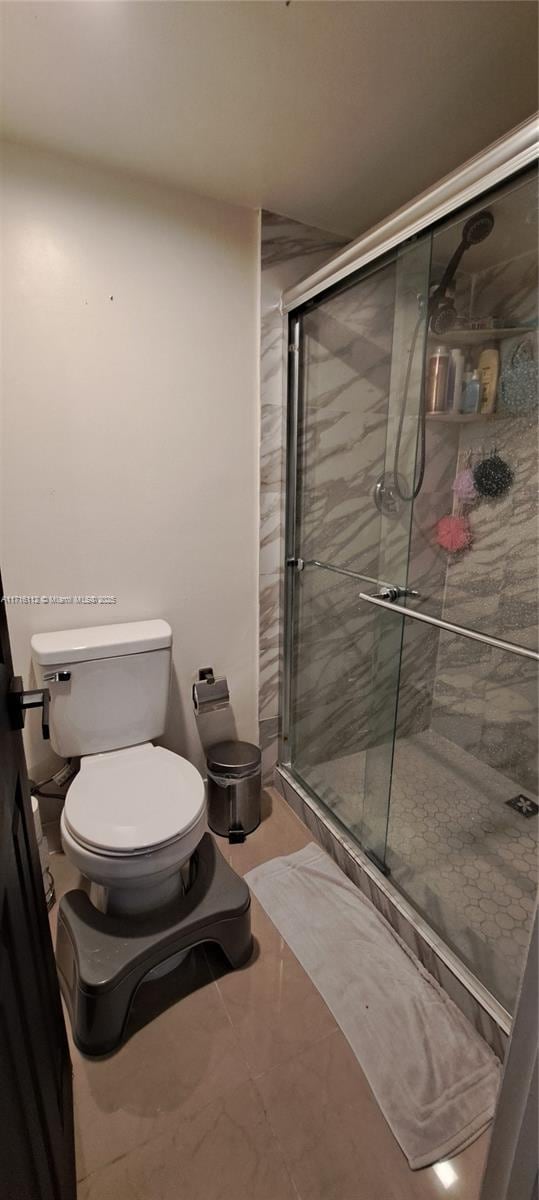 bathroom featuring toilet and a shower with shower door