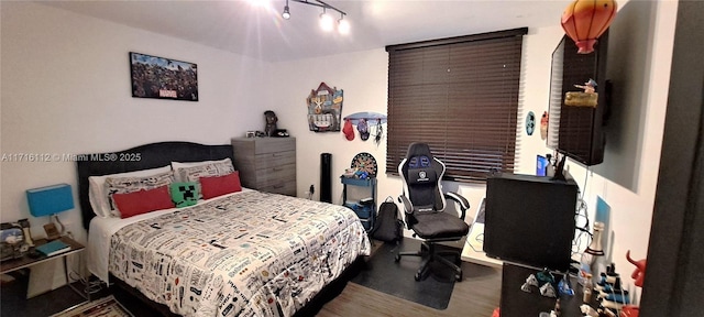 bedroom with hardwood / wood-style floors and track lighting