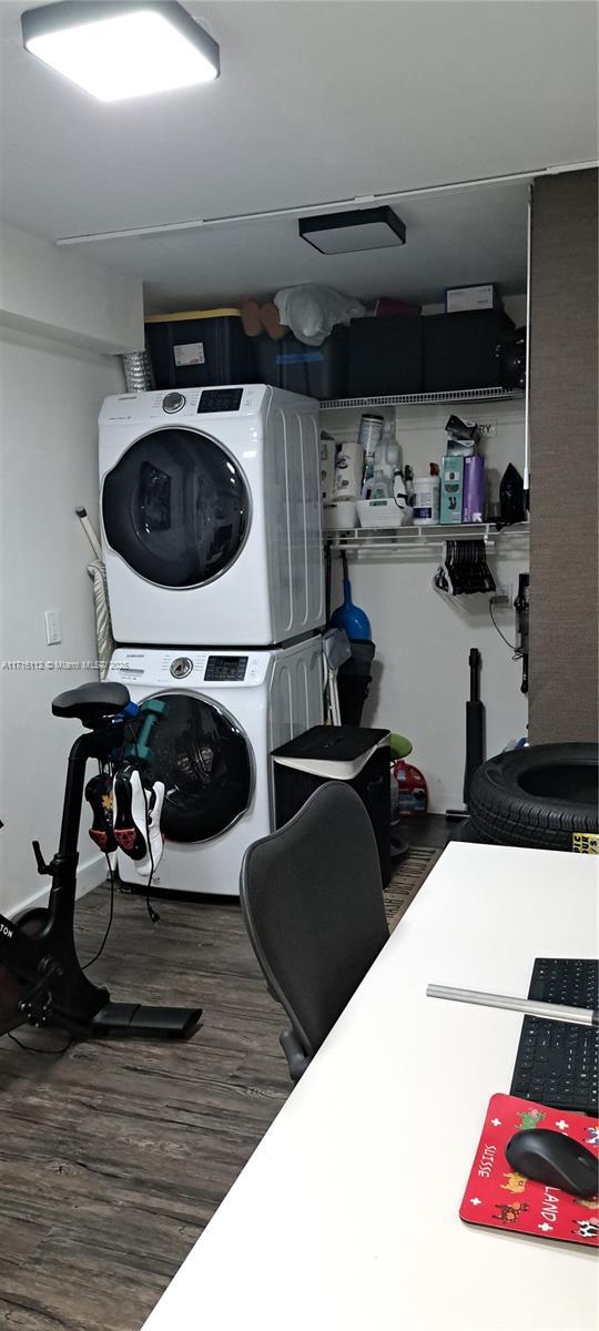 clothes washing area featuring dark wood-type flooring and stacked washer and clothes dryer