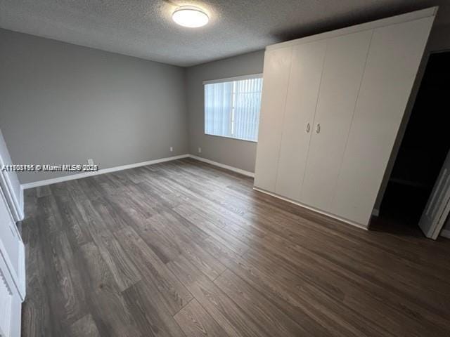 unfurnished bedroom with dark hardwood / wood-style flooring, a textured ceiling, and a closet