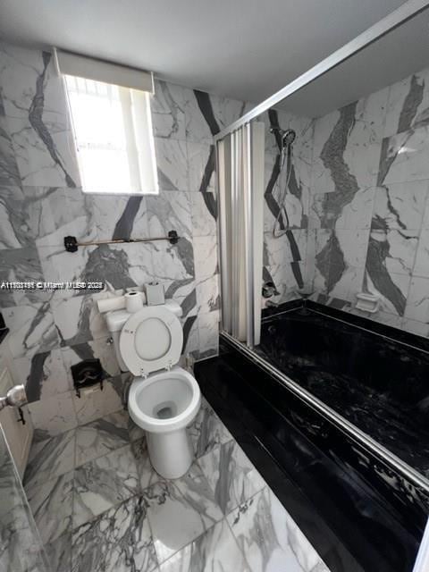 bathroom with toilet, walk in shower, and tile walls