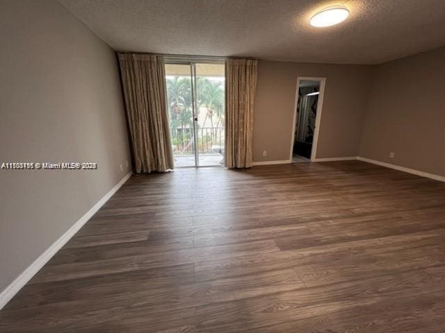 unfurnished room featuring dark hardwood / wood-style floors, a wall of windows, and a textured ceiling