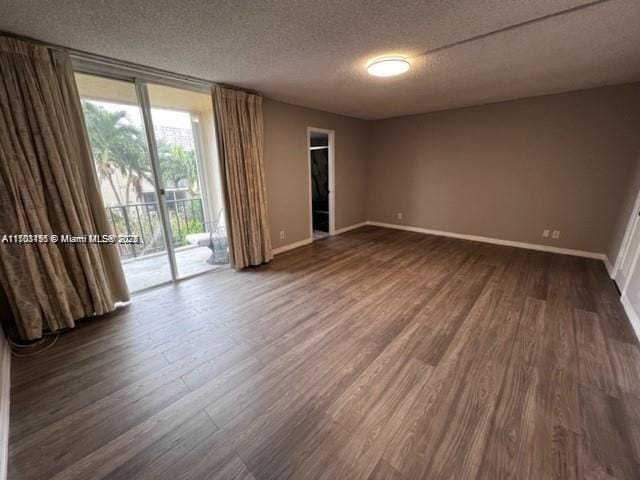 empty room featuring expansive windows, dark hardwood / wood-style flooring, and a textured ceiling